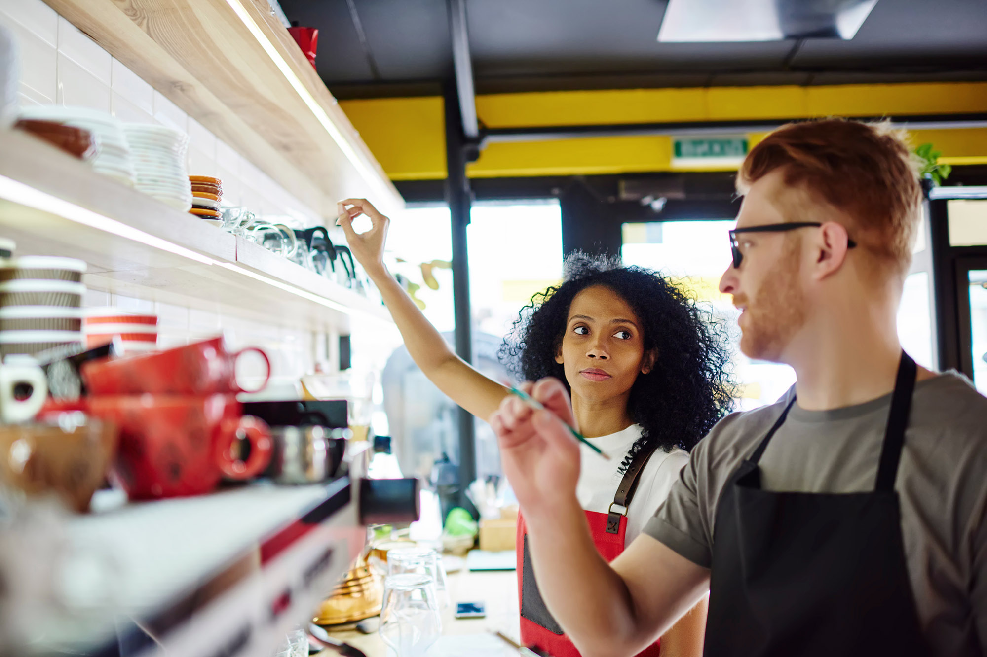 Two restaurant employees discuss inventory while looking at a shelf