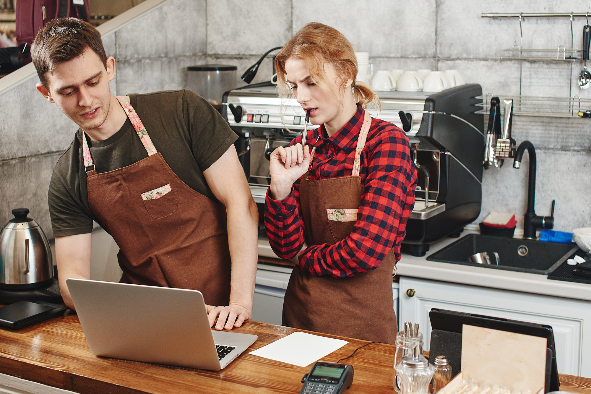 Two restaurant employees share a computer and discuss inventory