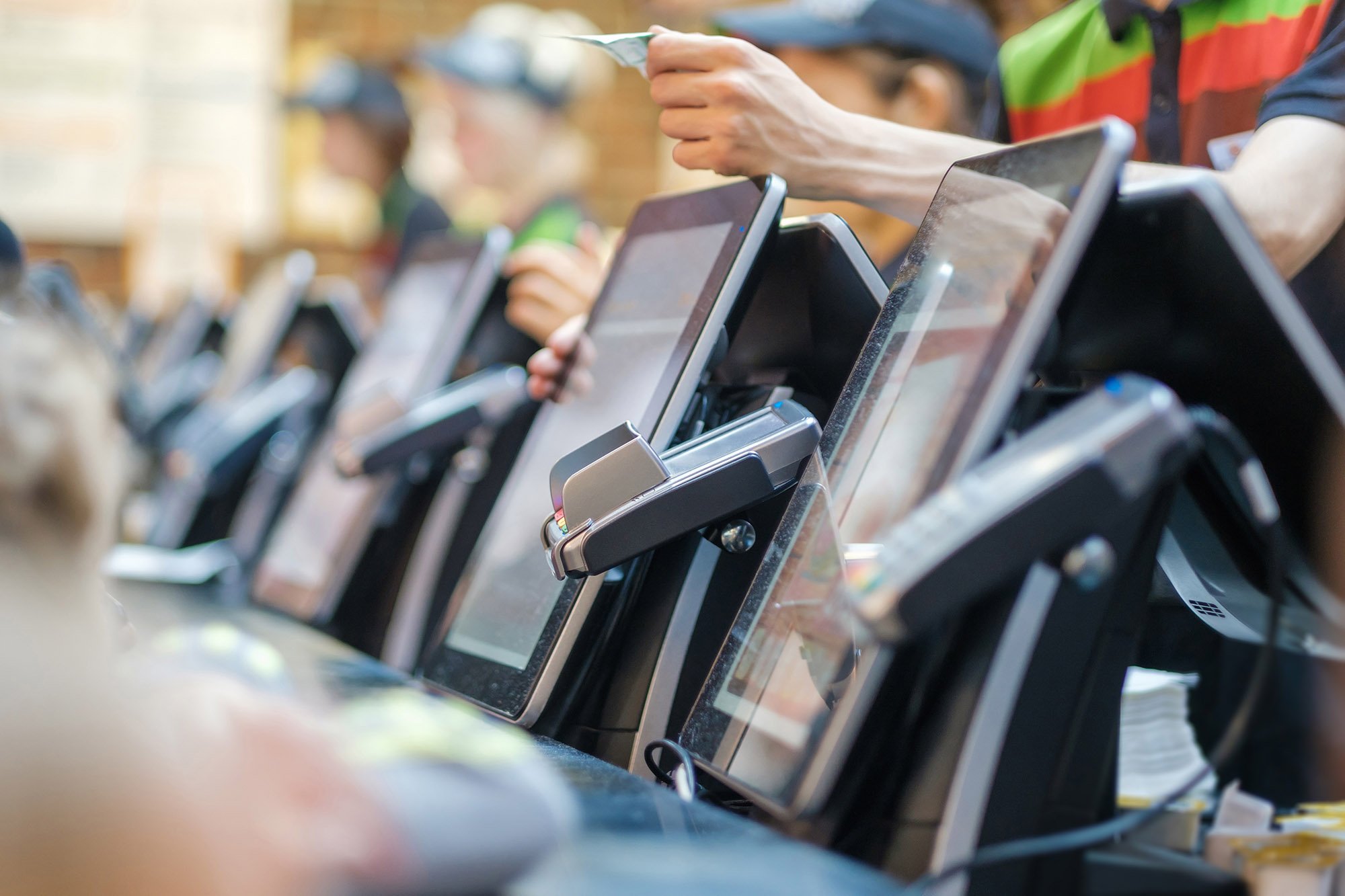 A row of POS machines at the front counter of a fast food restaurant